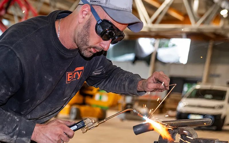 Un technicien Eury brase un tuyau au chalumeau